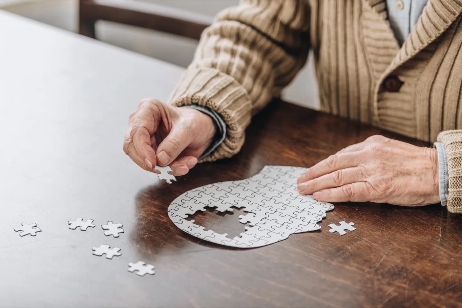 Personne âgée assemblant un puzzle en forme de tête, évoquant la stimulation cognitive
